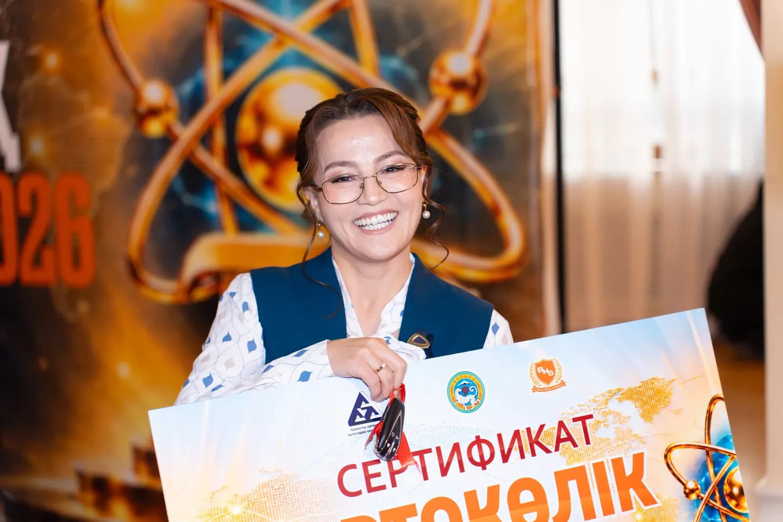 Учительница улыбается, держа сертификат на автомобиль